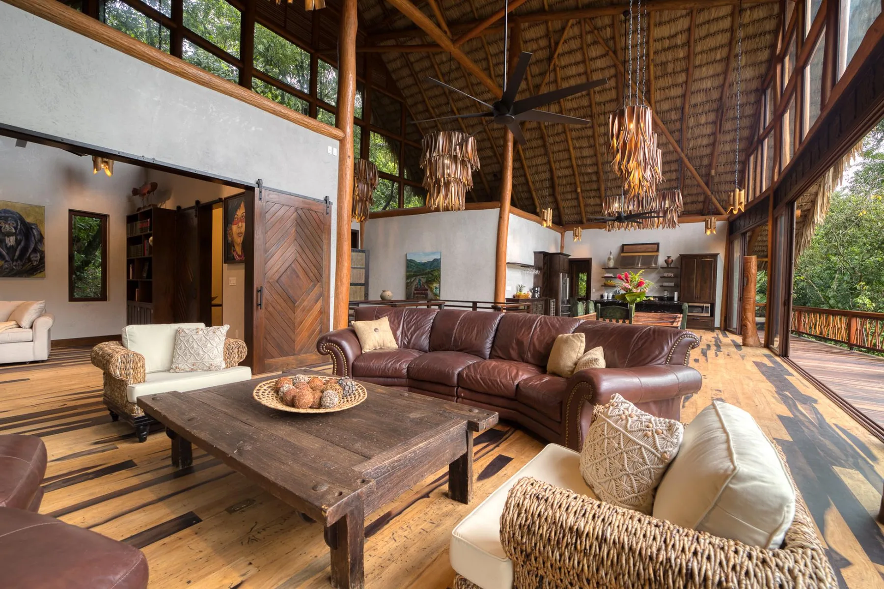 An open living room with brown seating beneath a high timber ceiling.