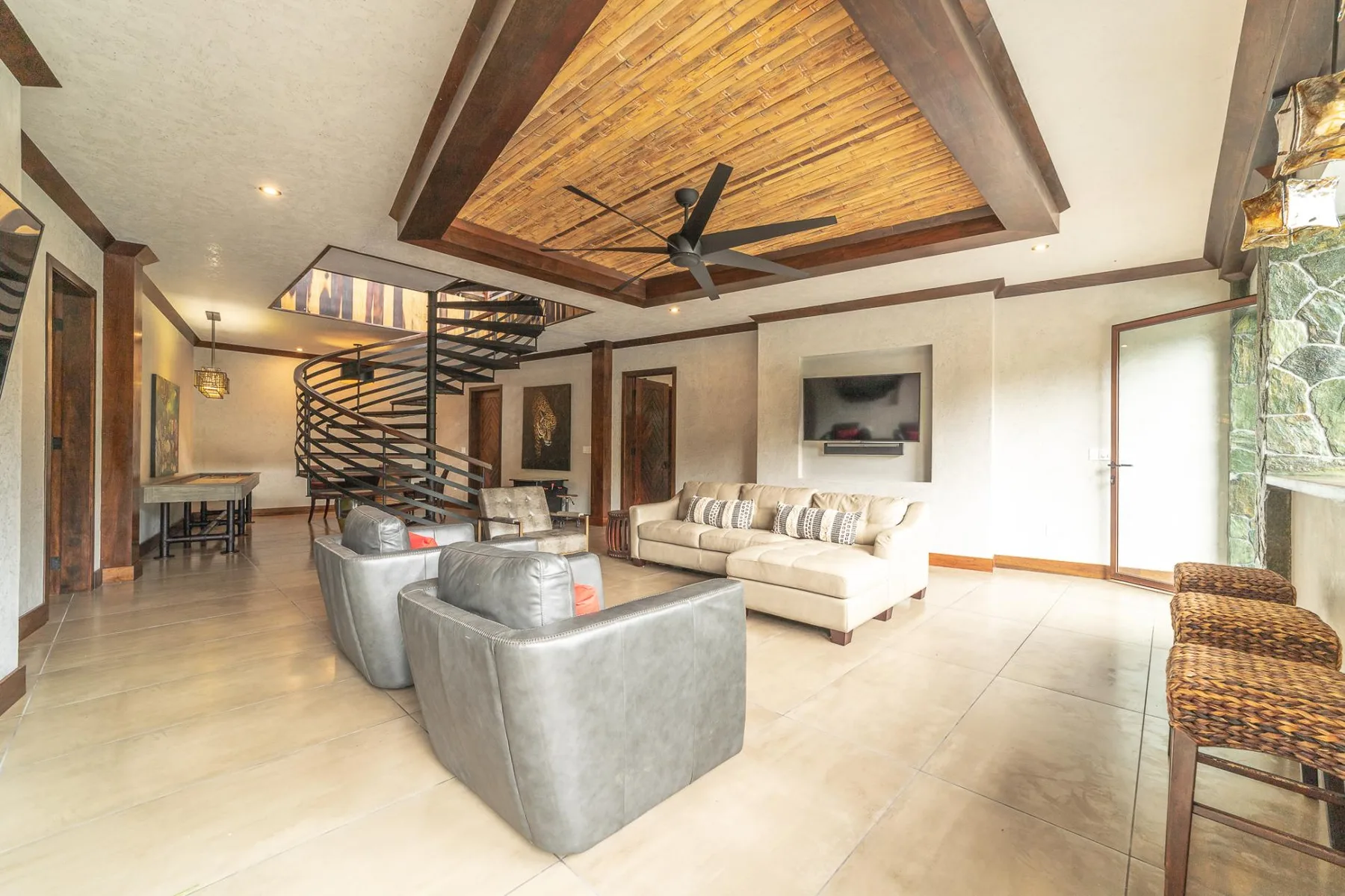 A spacious living room with seating beneath a wood-paneled ceiling.