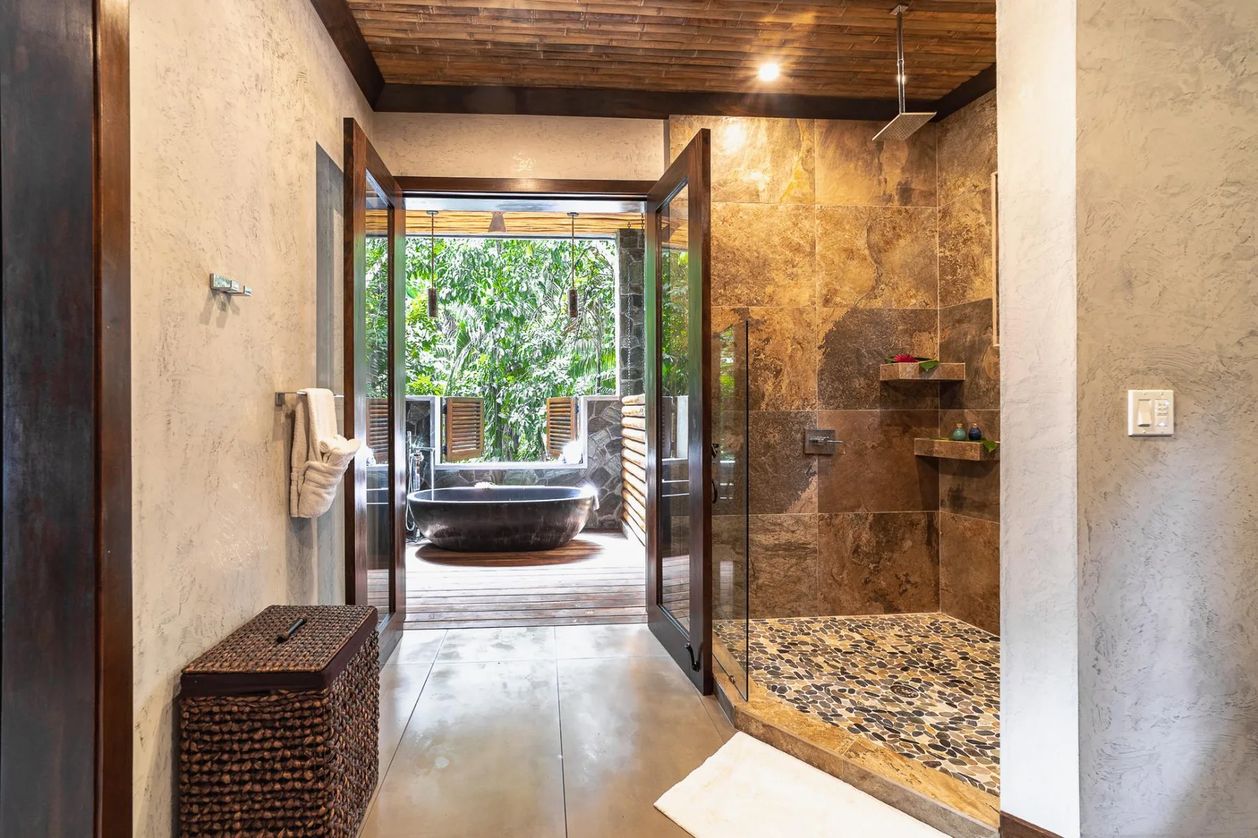 A bathroom with an open shower and a bathtub visible through the doorway.