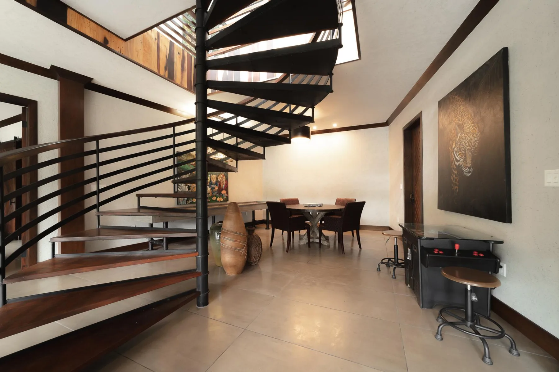 A dining area beneath a spiral staircase, with a table and seating.
