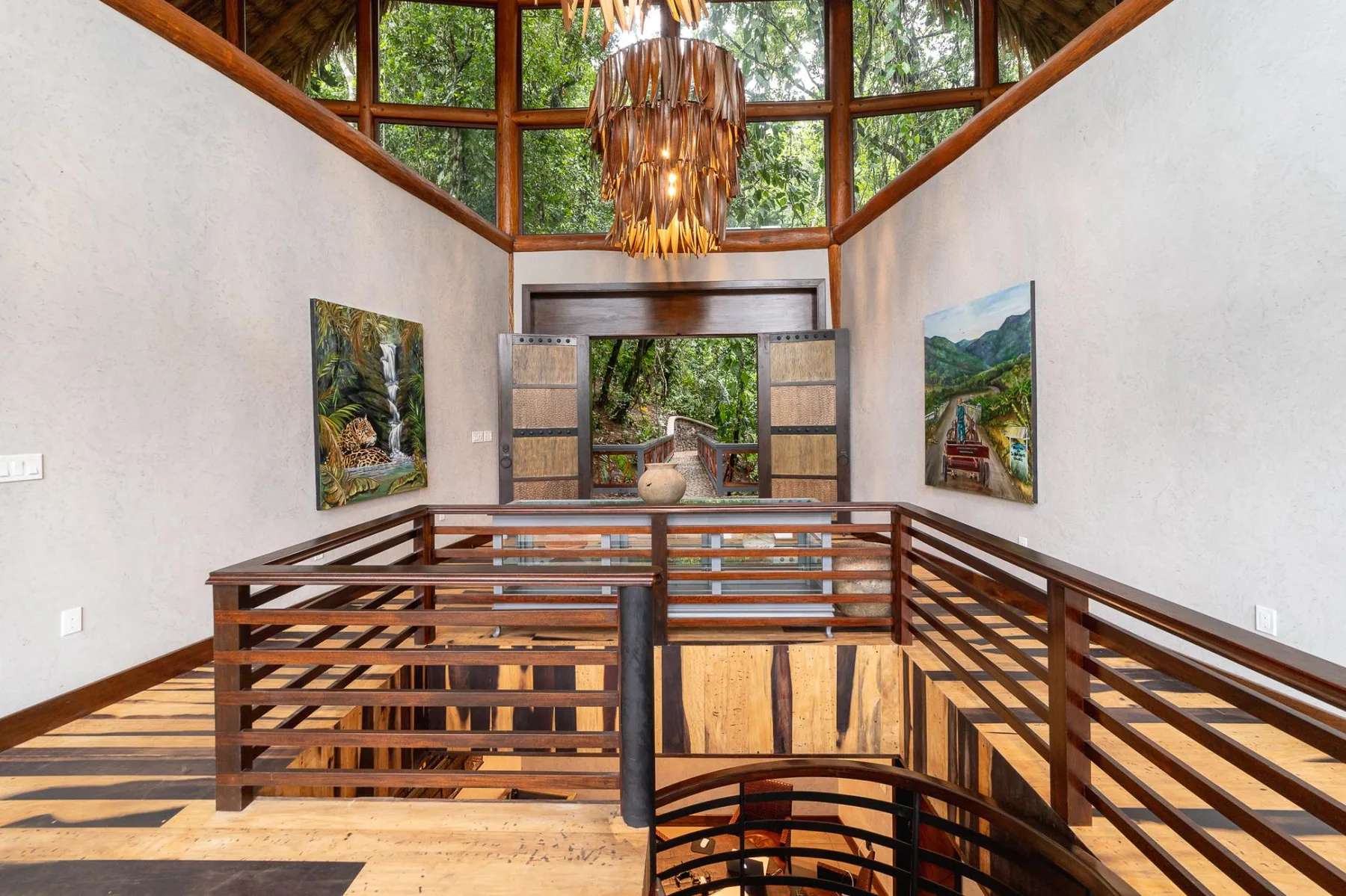 An open wooden interior walkway overlooks a lower level beneath tall windows.