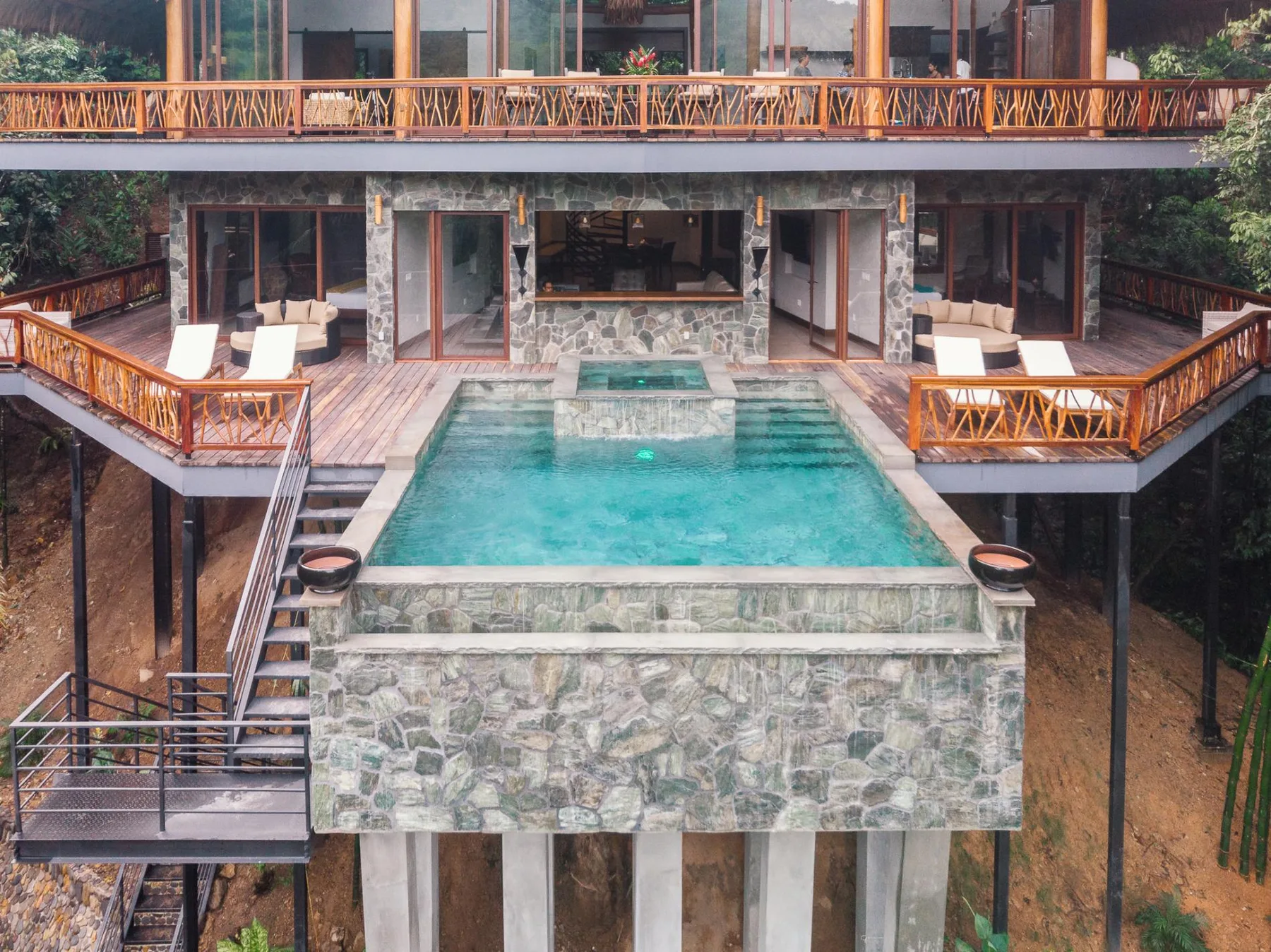 A swimming pool sits between wooden decks in front of a modern building.
