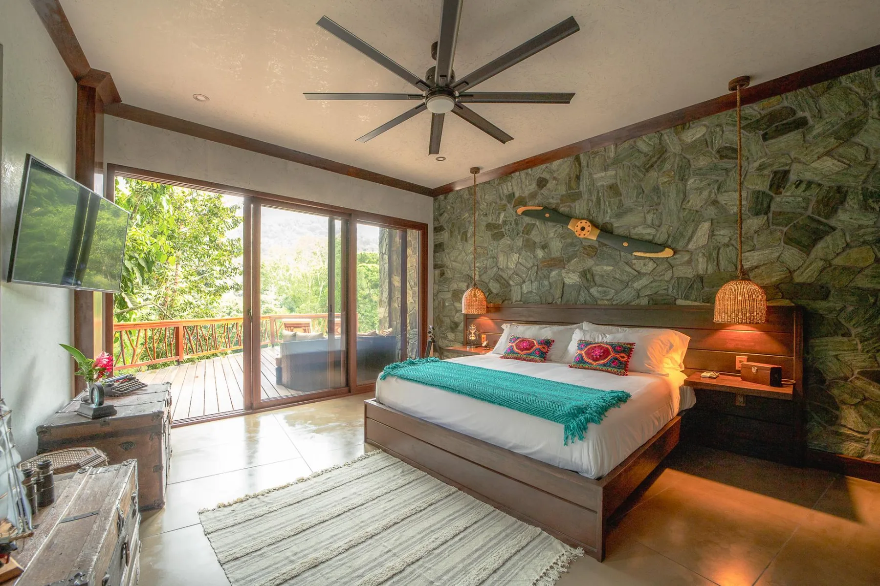 A bedroom with a bed, sliding glass doors, and a view of the green outdoors.