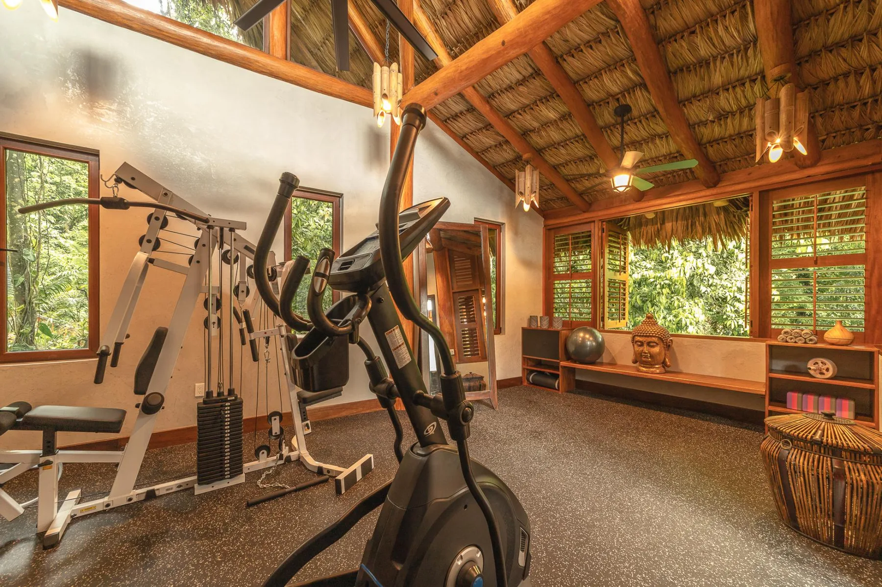 A workout room with exercise equipment beneath a high wooden-beamed ceiling.