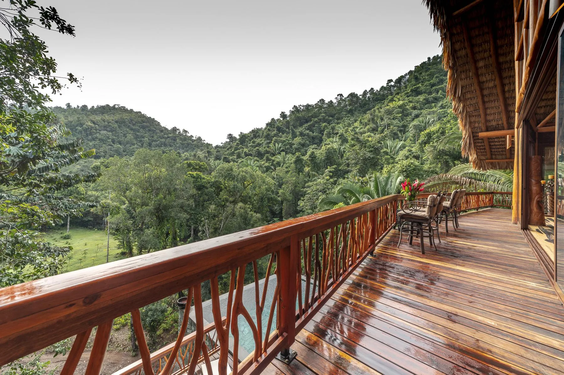 A wooden balcony overlooks a lush, forested hillside.