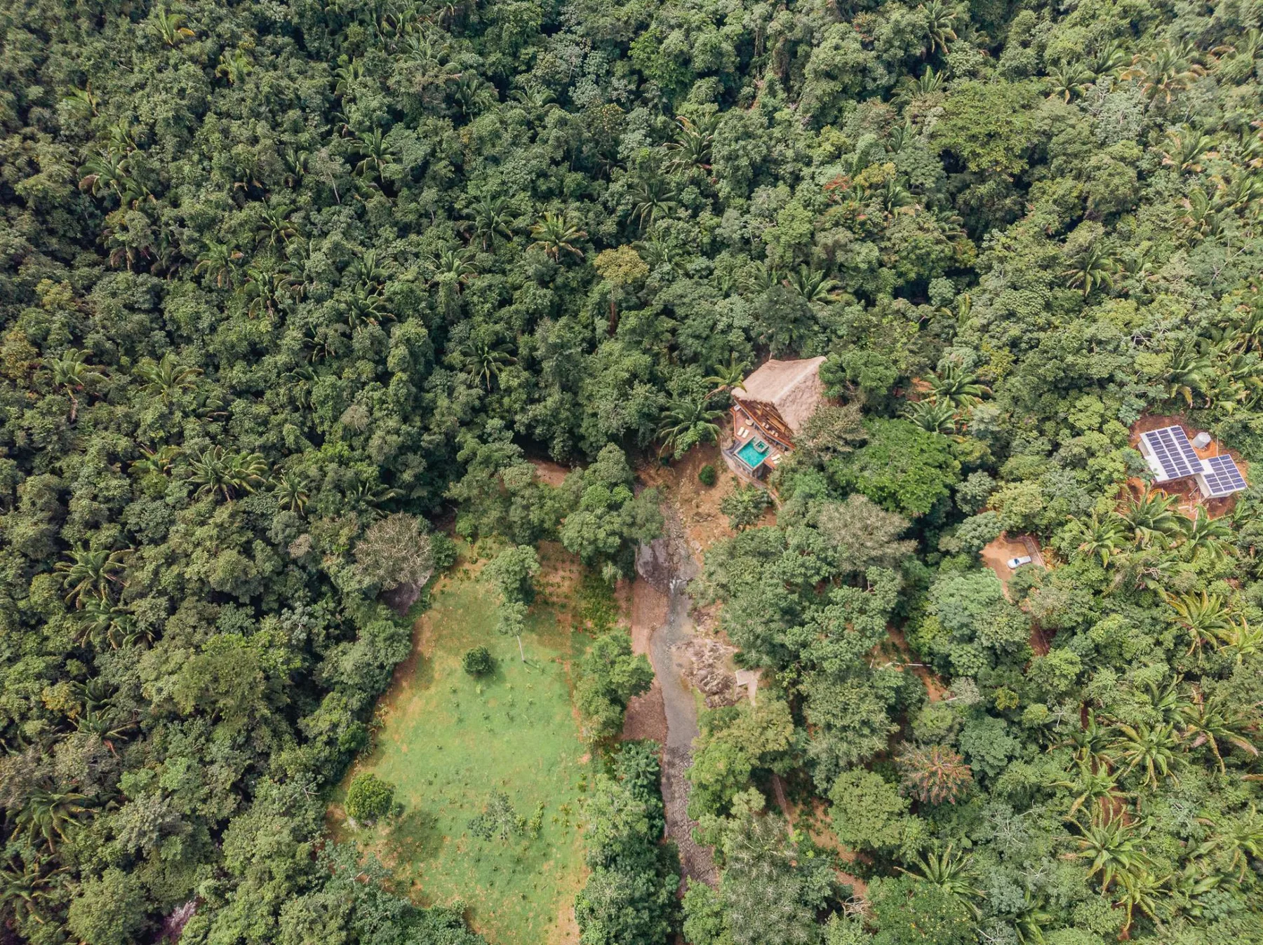 Aerial view of a forested property with a small clearing and buildings.