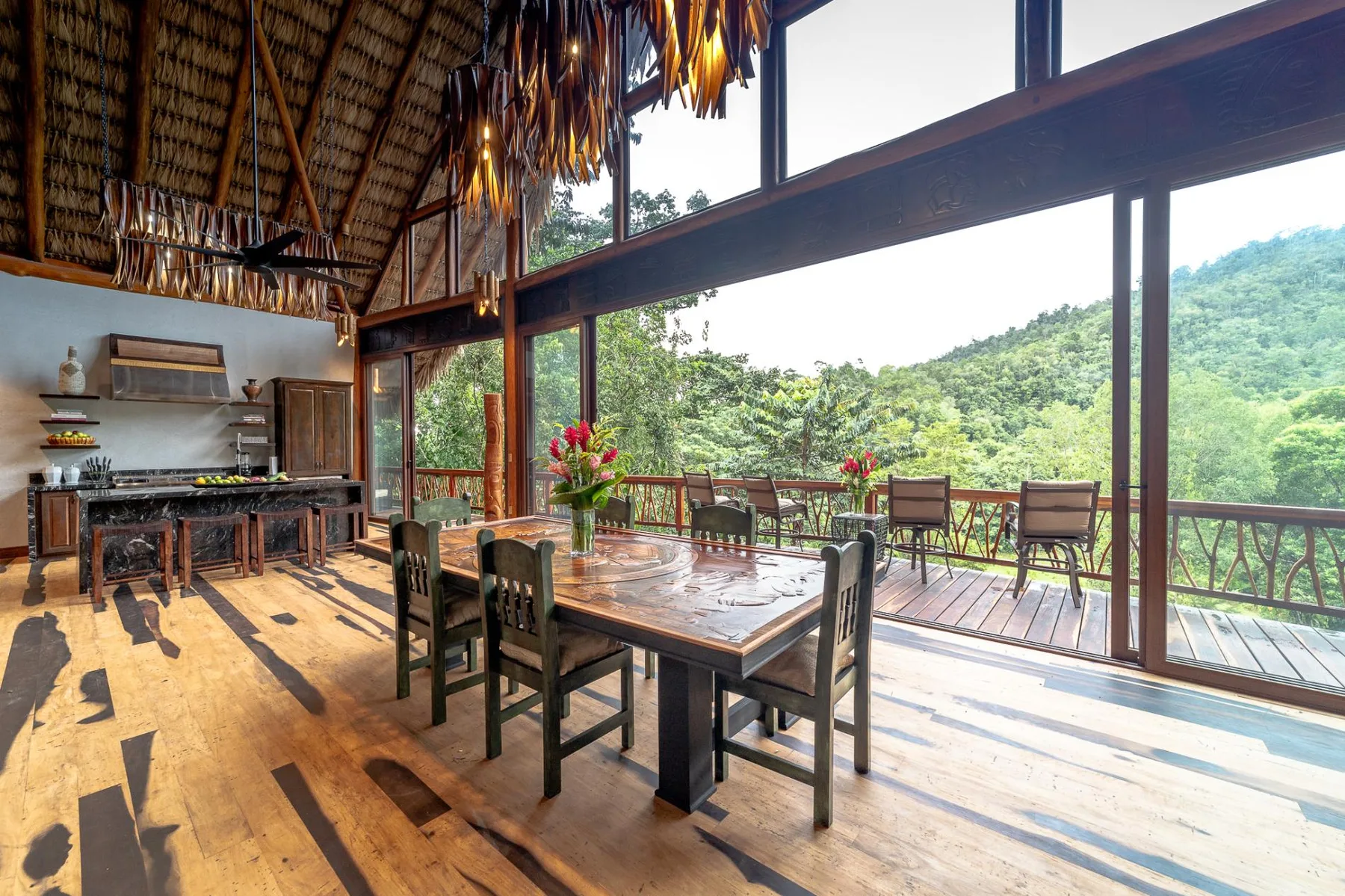 An open dining area with wooden tables overlooks a green hillside.