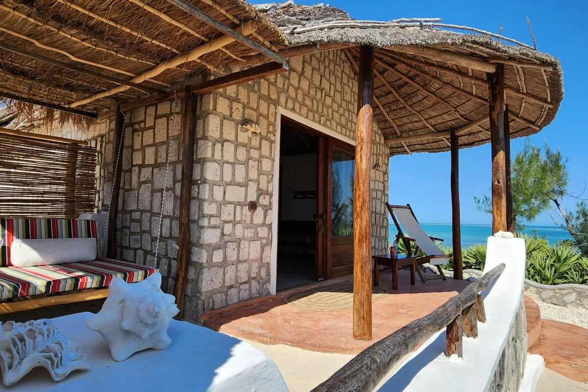 Una terraza exterior con techo de paja y asientos empotrados da al mar.