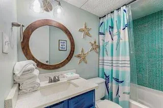 Un lavabo de baño con espejo redondo está junto a una cortina de ducha.