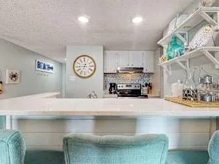 Una cocina luminosa con una barra larga y asientos color turquesa.