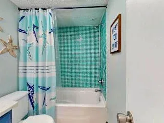 Un baño con bañera, cortina de ducha y pared de azulejos verdes.