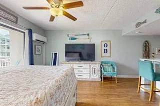 Un dormitorio con una cama grande, un televisor y un ventilador de techo.