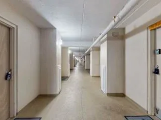 Zona común: Un largo pasillo interior con puertas y tuberías en el techo.