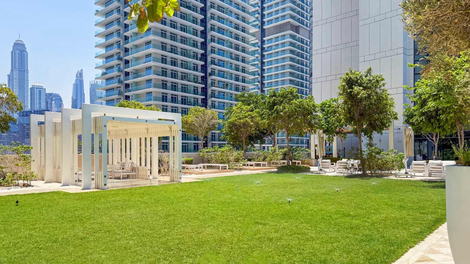 Shared amenity: A landscaped courtyard with a broad lawn, trees, and high-rise buildings.