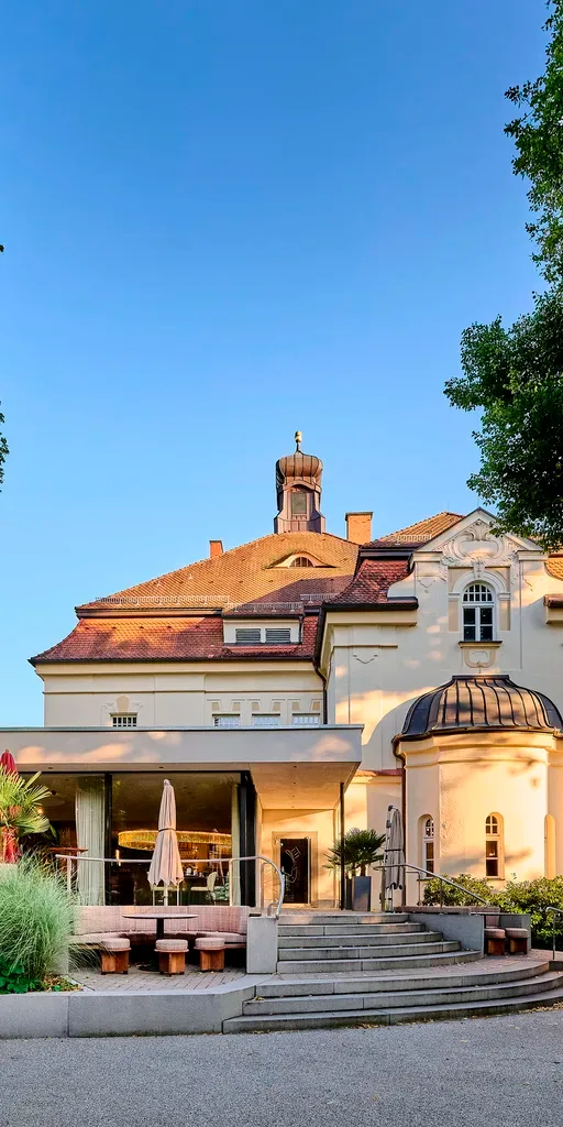 Representative hotel space: A large building with a red-tiled roof stands beside a paved terrace.