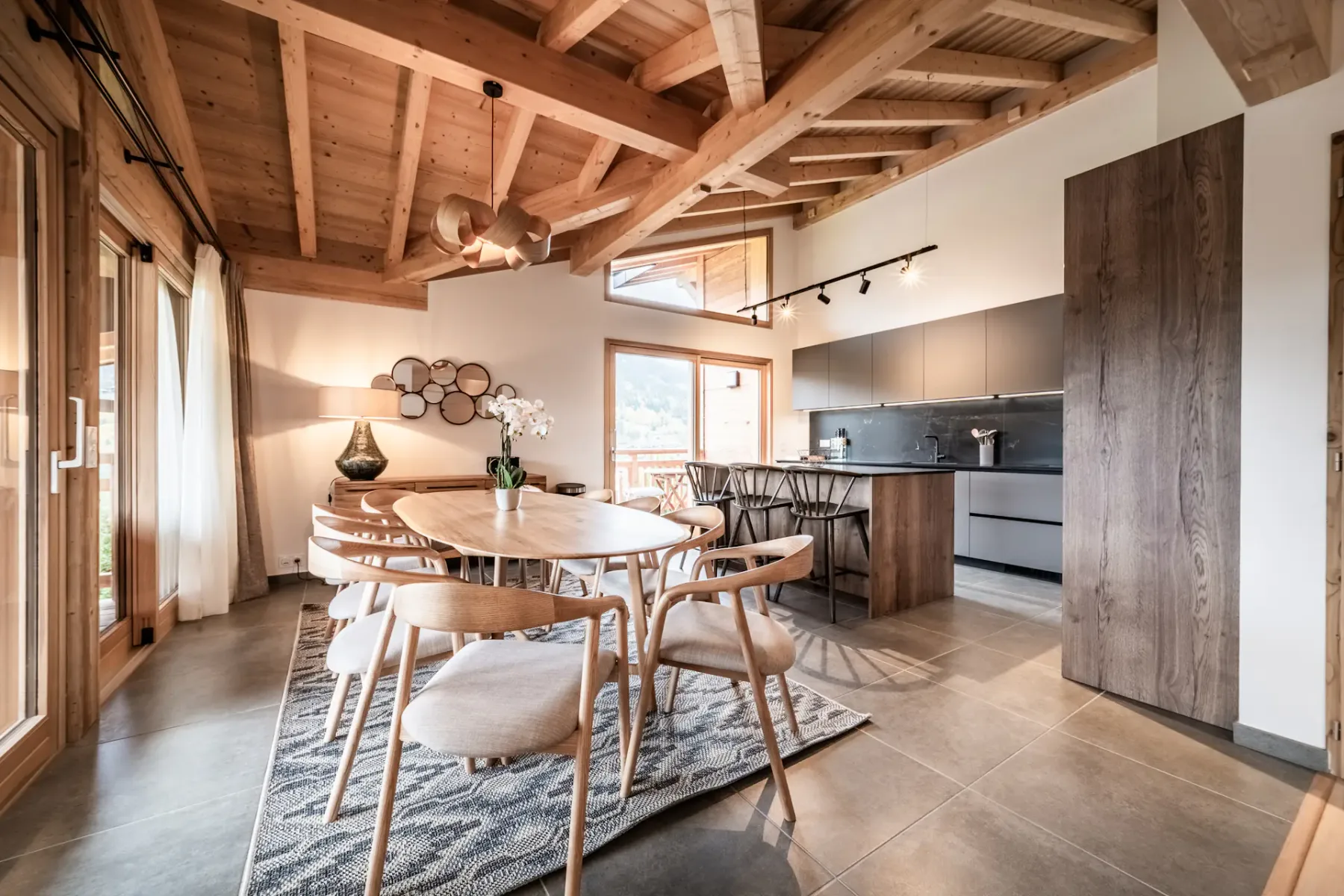 Un espacio abierto de comedor y cocina con una mesa de madera bajo vigas expuestas.