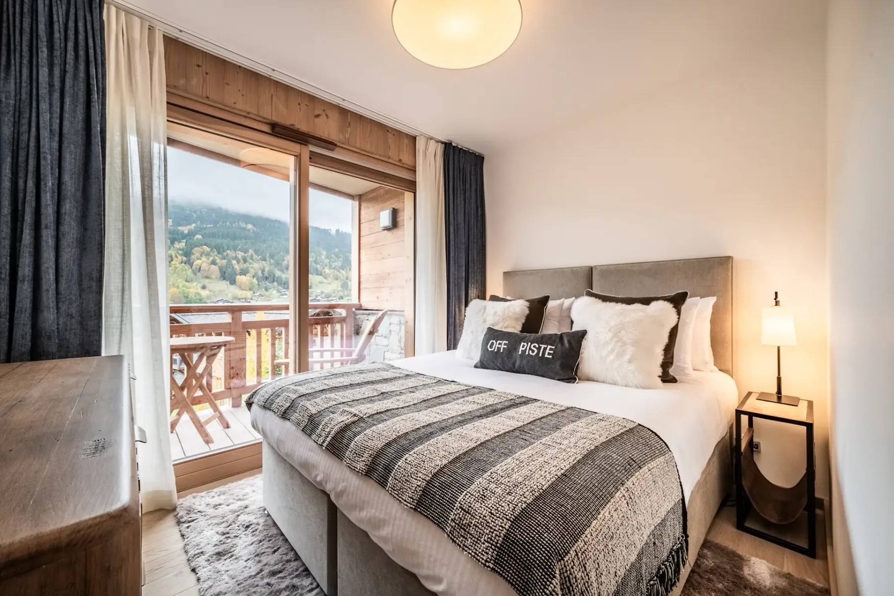 Un dormitorio con una cama tendida junto a una puerta de cristal que da a un balcón.