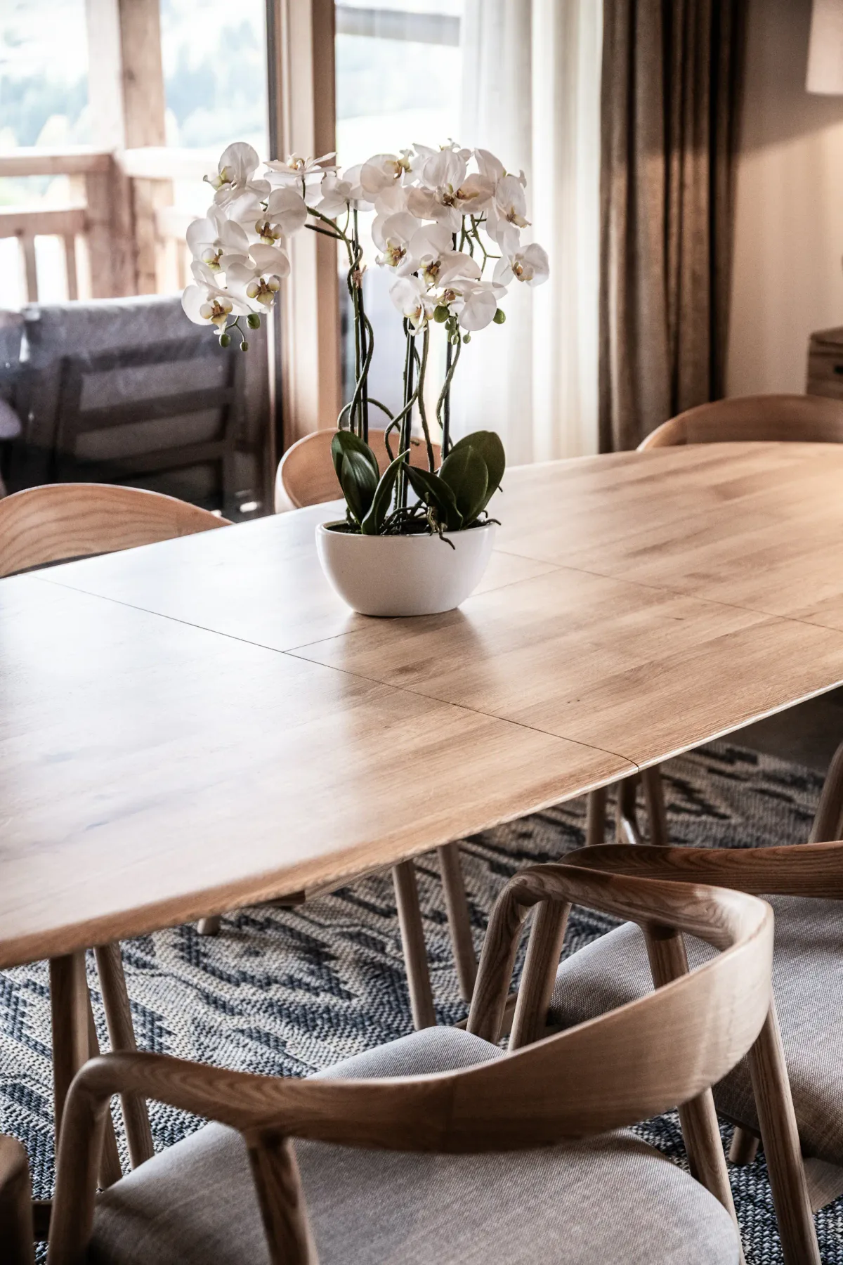 Comedor con una mesa de madera, sillas y una orquídea en maceta.