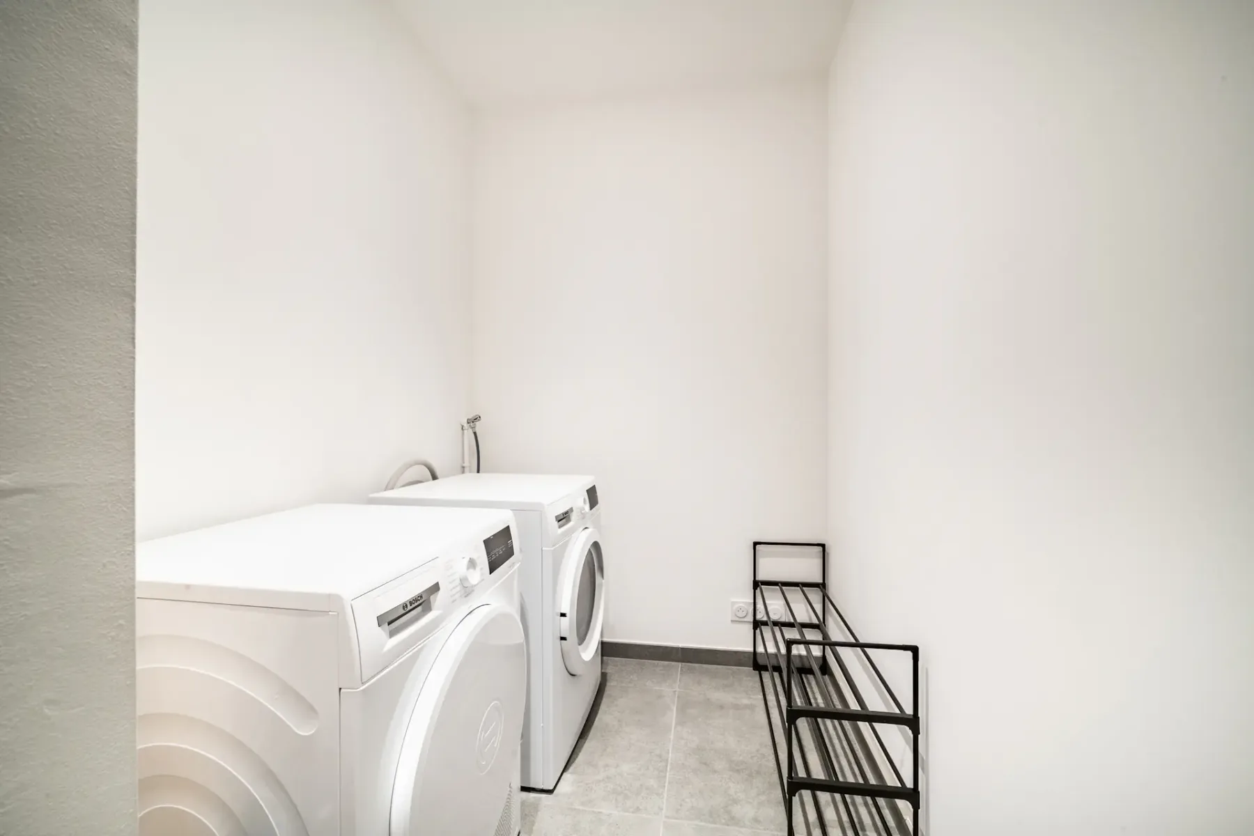 Un cuarto de lavado con lavadoras y un tendedero metálico.