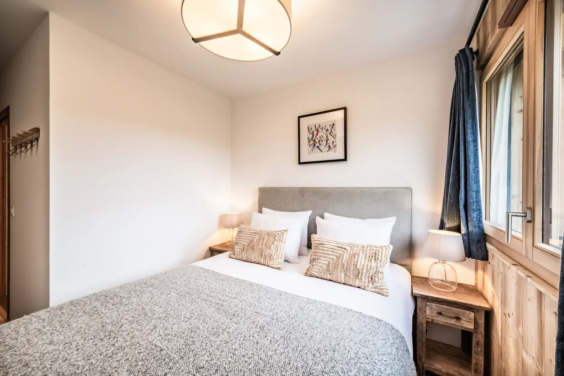 Un dormitorio con una cama bien tendida y una ventana grande.
