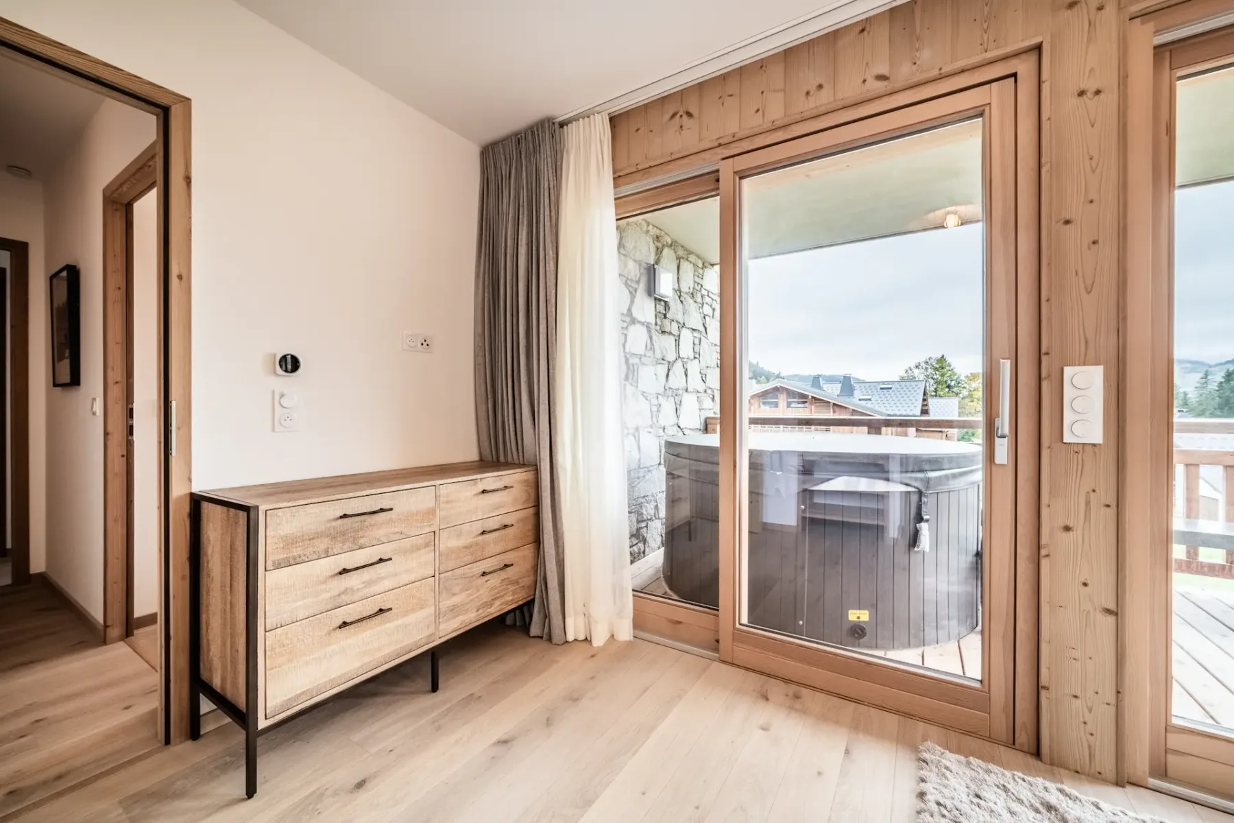 Un dormitorio luminoso da a un balcón a través de una gran puerta de cristal.
