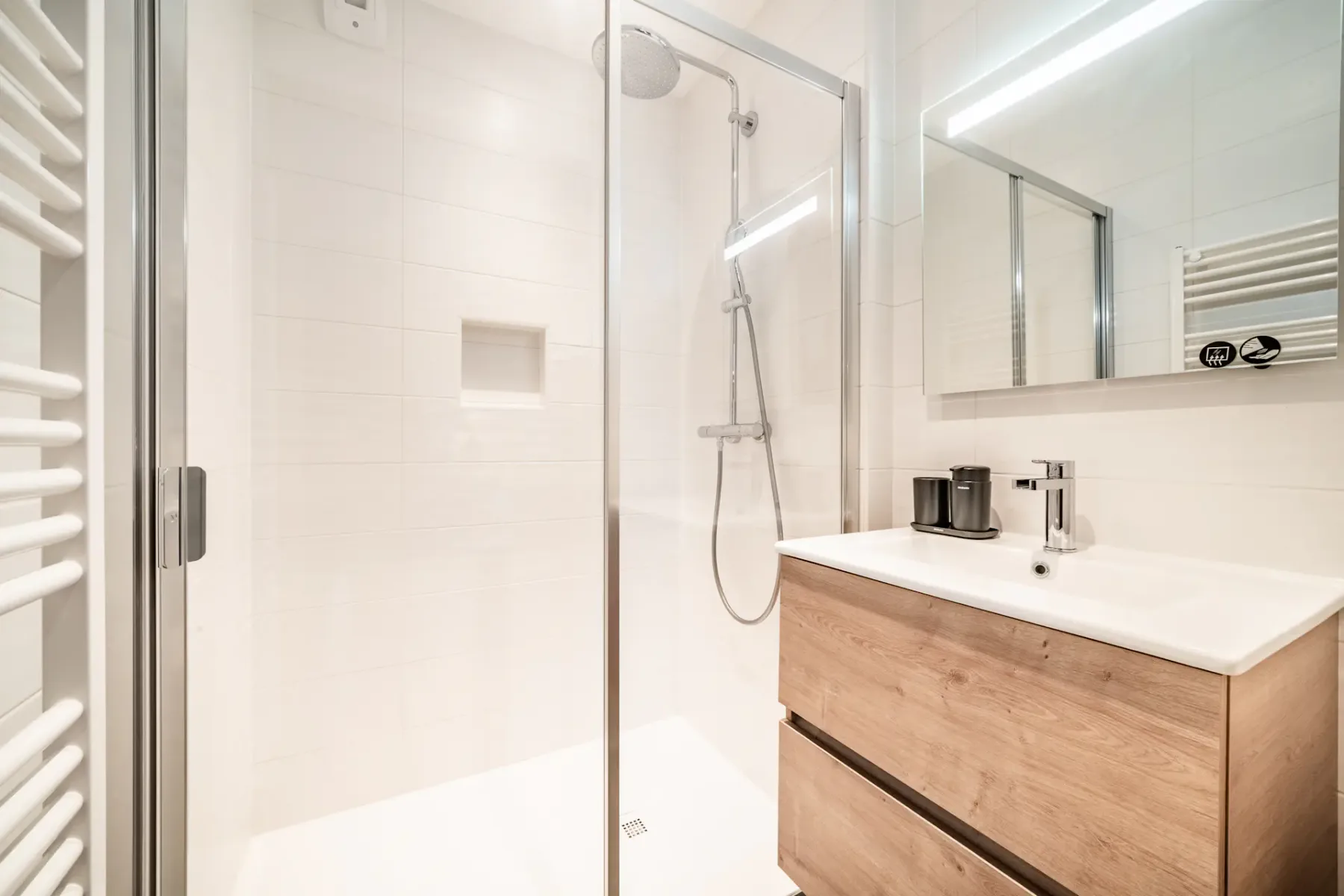 Un baño luminoso con una ducha de vidrio y un mueble de lavabo de frente de madera.