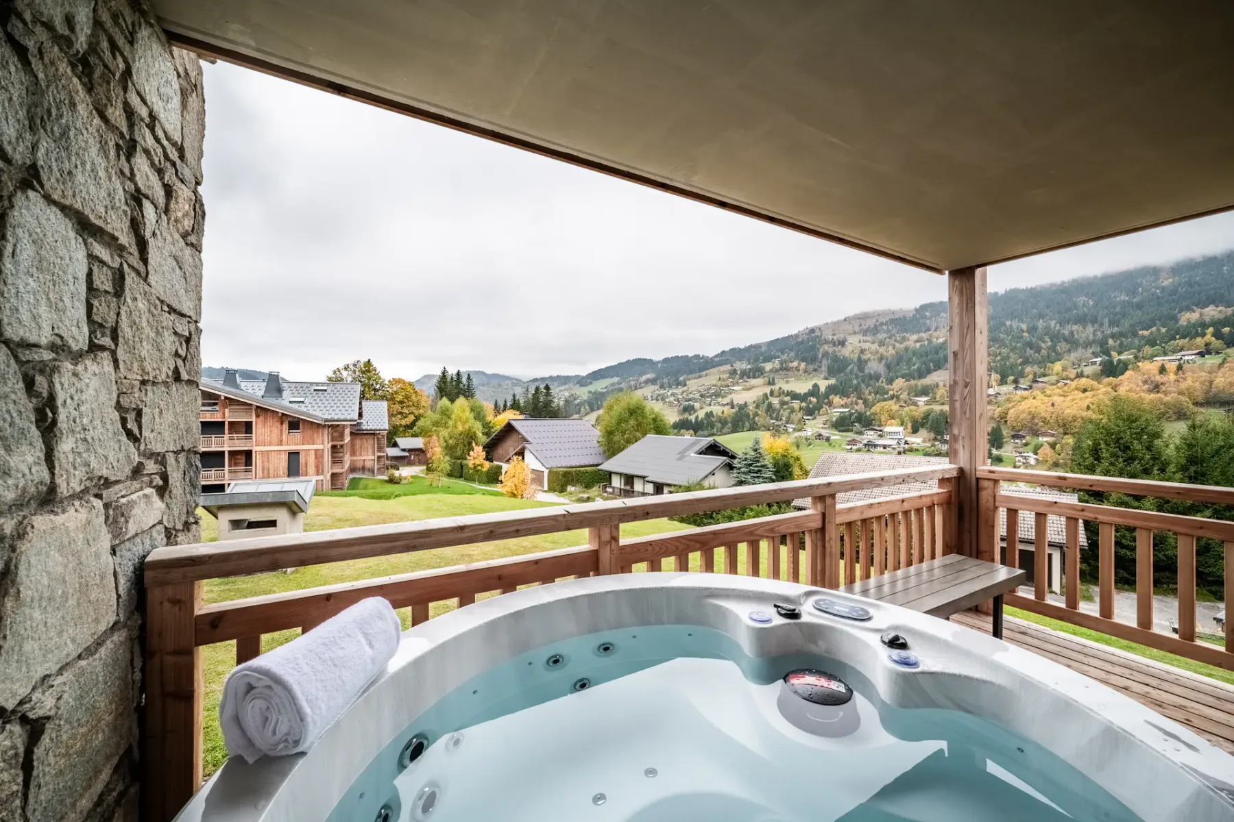 Un balcón cubierto cuenta con una bañera de hidromasaje con vistas a un valle montañoso.