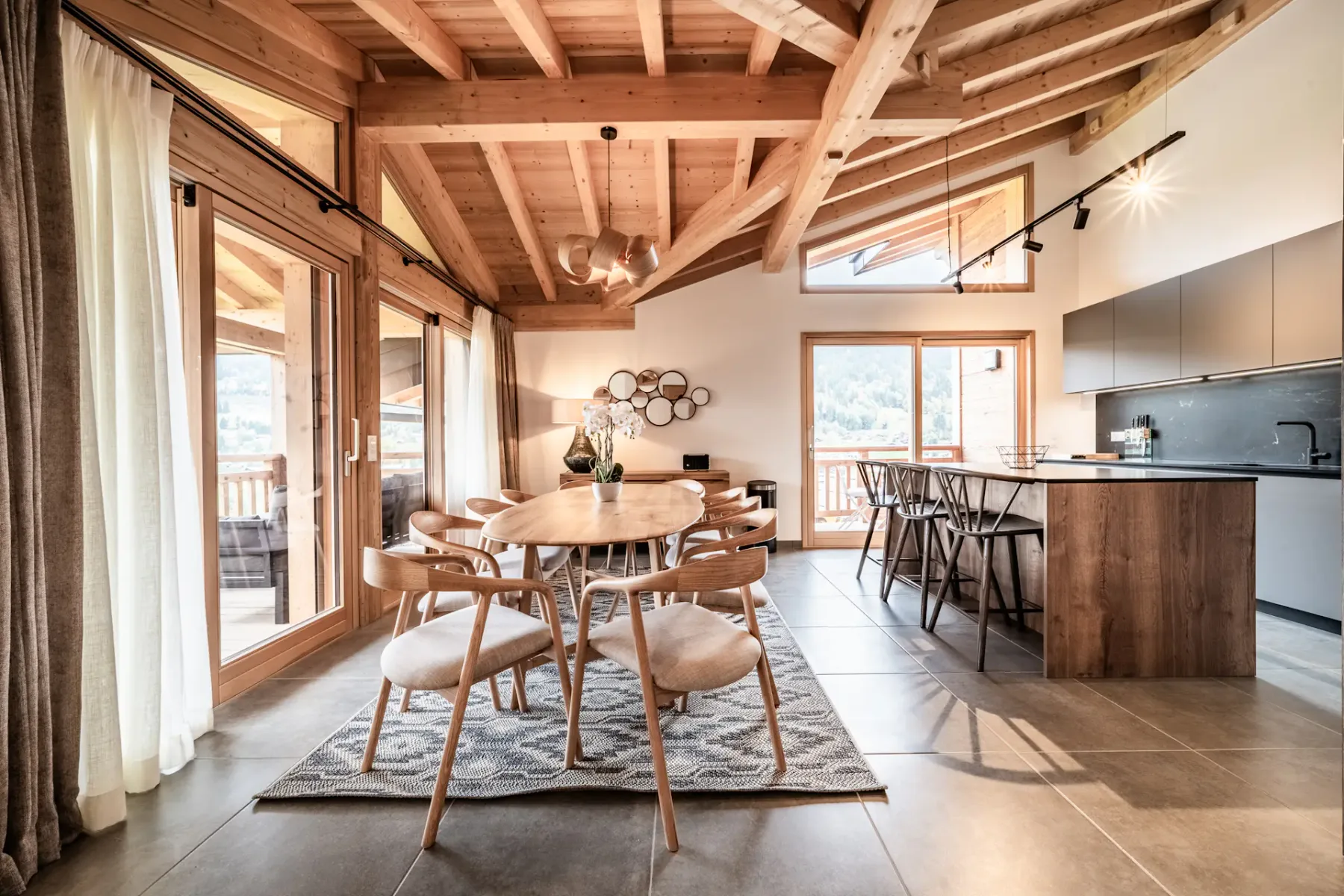 Comedor junto a una cocina abierta, con una mesa de madera y sillas.