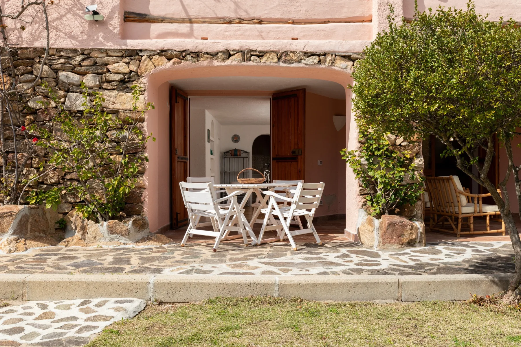 An outdoor patio has a white dining set beneath an arched doorway.