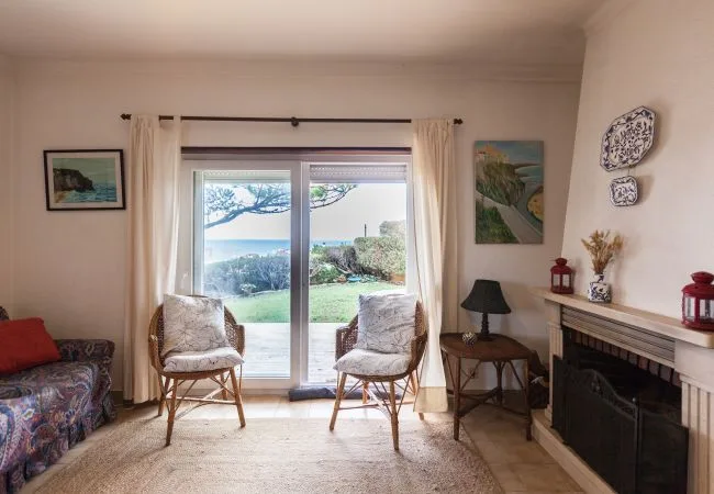 Una sala de estar con dos sillones frente a una puerta de vidrio que da a un jardín.