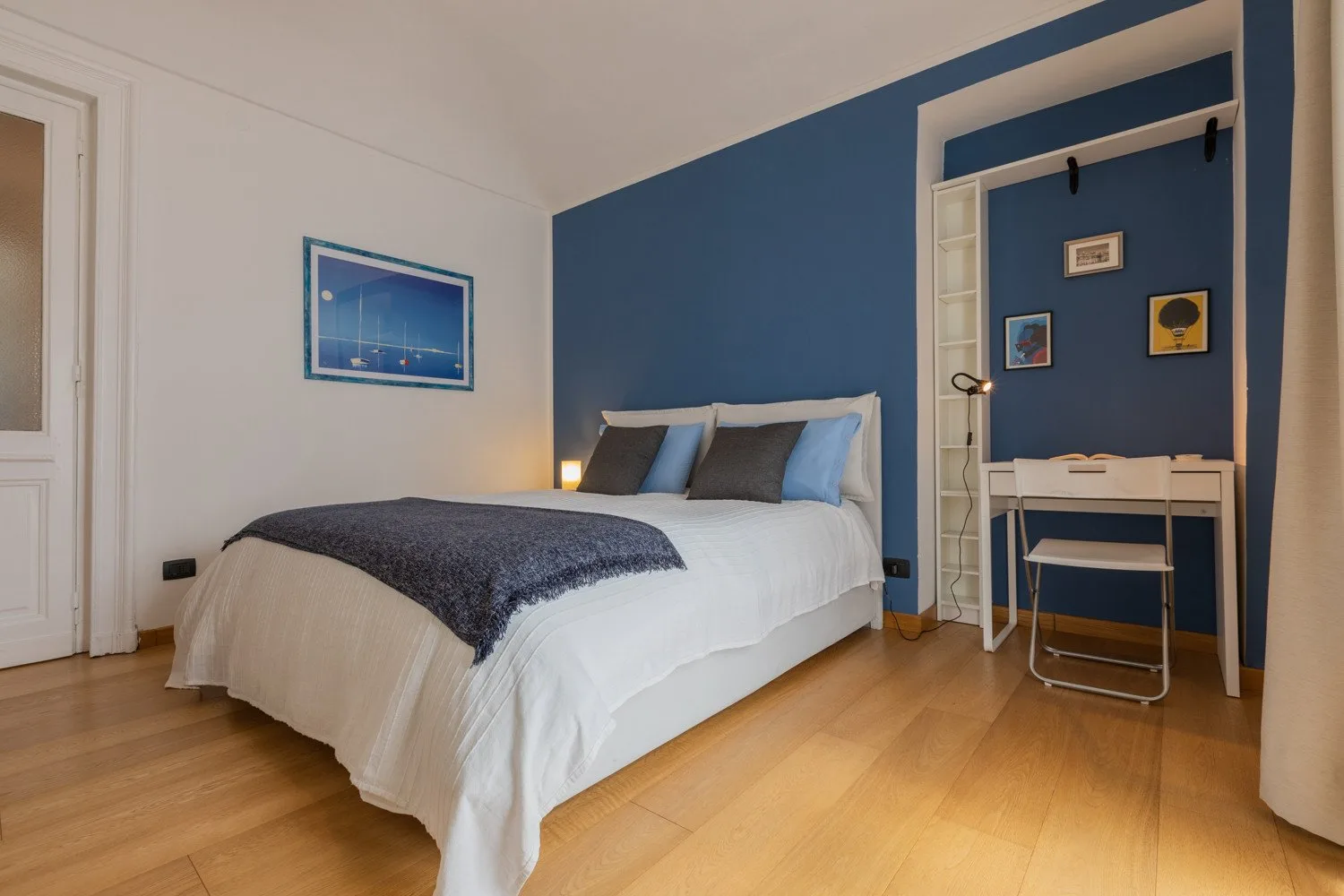 Un dormitorio con una cama y un escritorio pequeño junto a una pared azul.