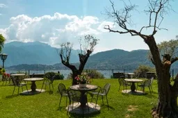 Representative hotel space: Outdoor dining area with tables and chairs on a grassy lawn overlooking mountains.