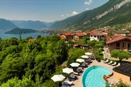 Representative hotel space: A lakeside resort scene with a curved pool, outdoor seating, and mountain views.