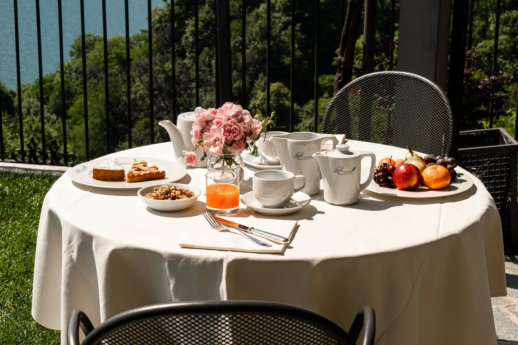 Representative hotel space: An outdoor dining table is set with tea, pastries, fruit, and flowers.
