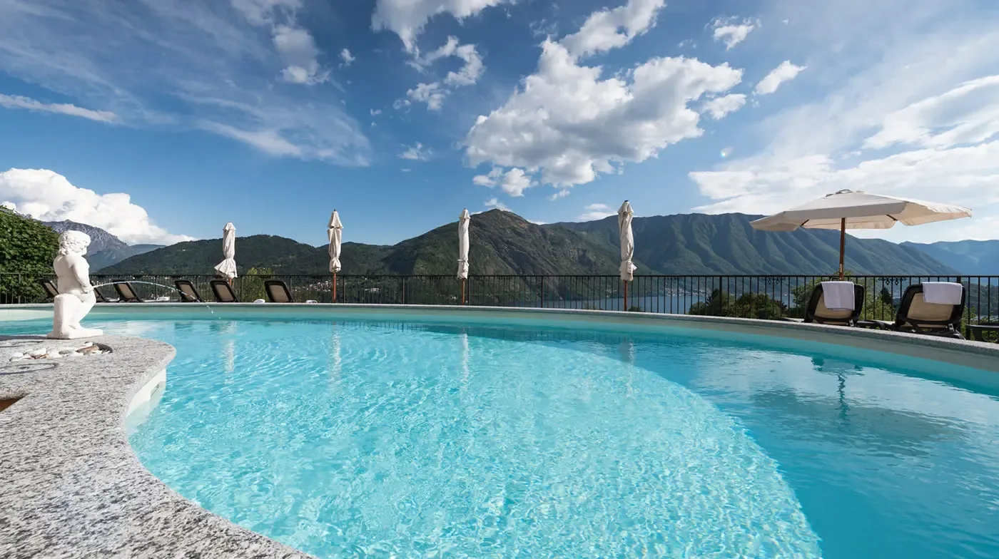 Representative hotel space: An outdoor swimming pool overlooks mountains beneath a partly cloudy sky.