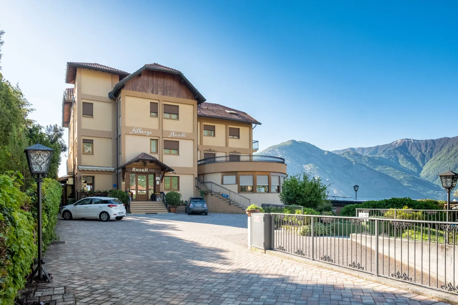 Representative hotel space: A multi-story hotel building stands beside a paved driveway with mountains in the background.