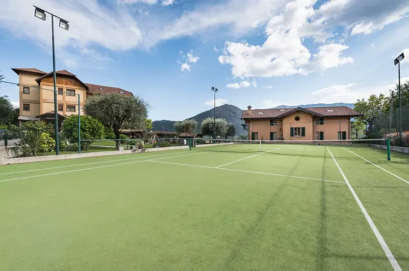 Representative hotel space: An outdoor tennis court sits in front of buildings and a mountain.