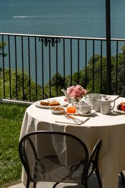 Representative hotel space: A dining table with flowers and refreshments overlooks the water from a balcony.