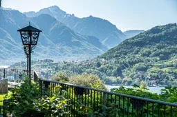 Representative hotel space: A mountain lake view framed by a garden railing and a decorative lamp.