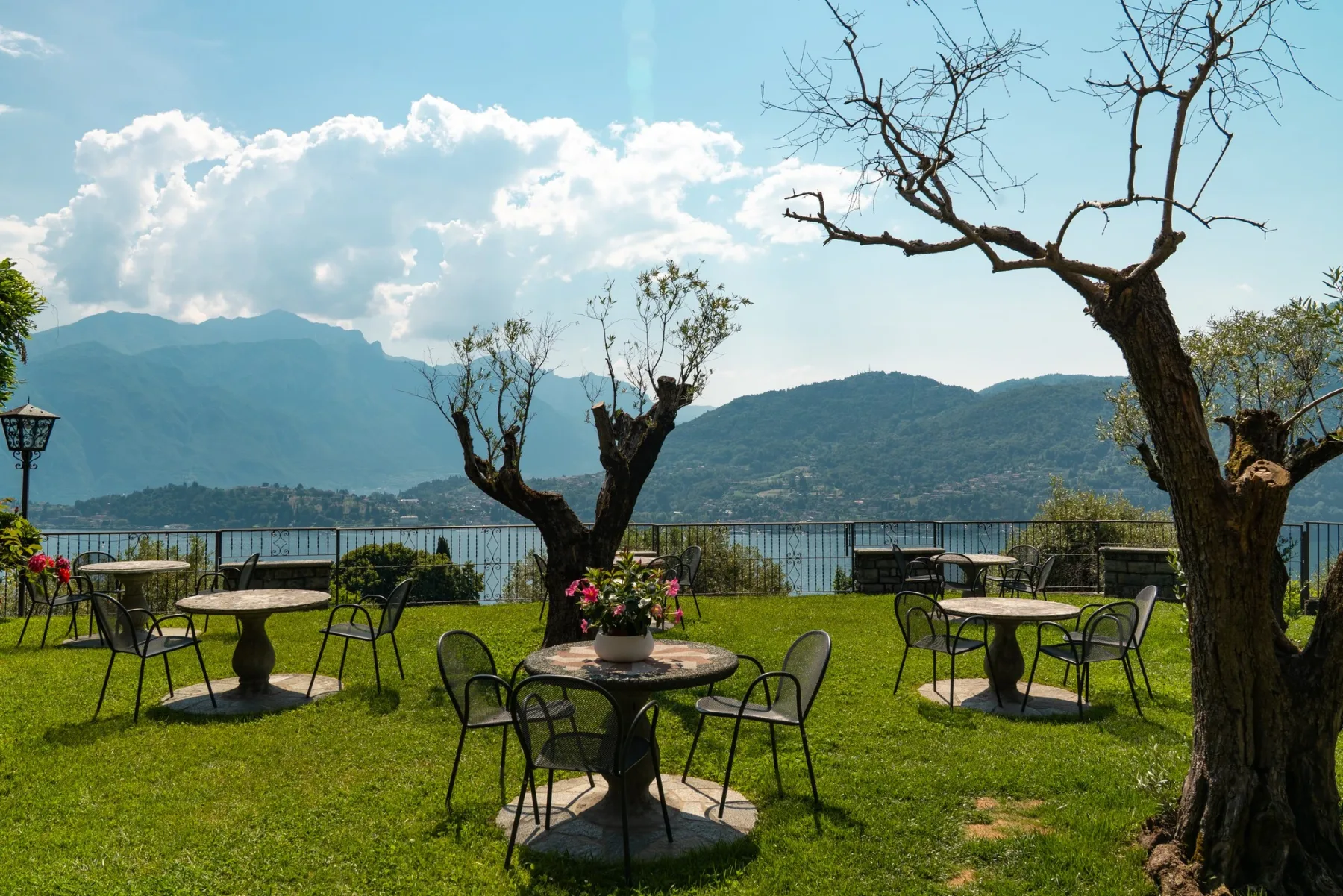 Representative hotel space: Outdoor dining area with tables and seating overlooking a lake and mountains.