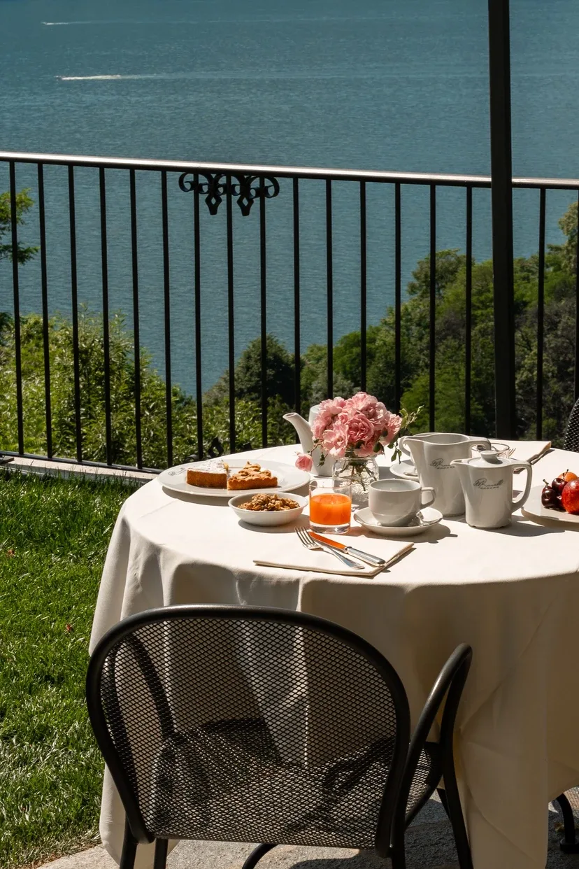 Representative hotel space: A dining table set for tea sits beside a railing overlooking the water.