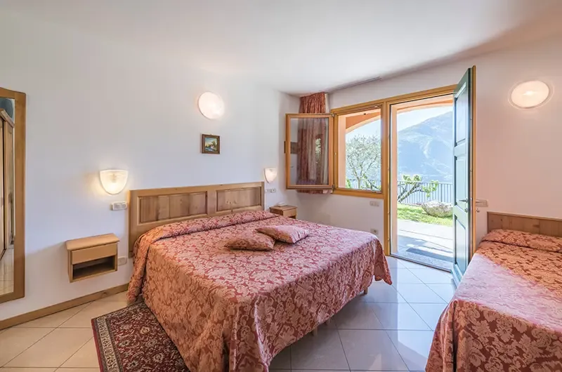 Representative hotel space: A bedroom with patterned bedding, a window, and an open balcony door.
