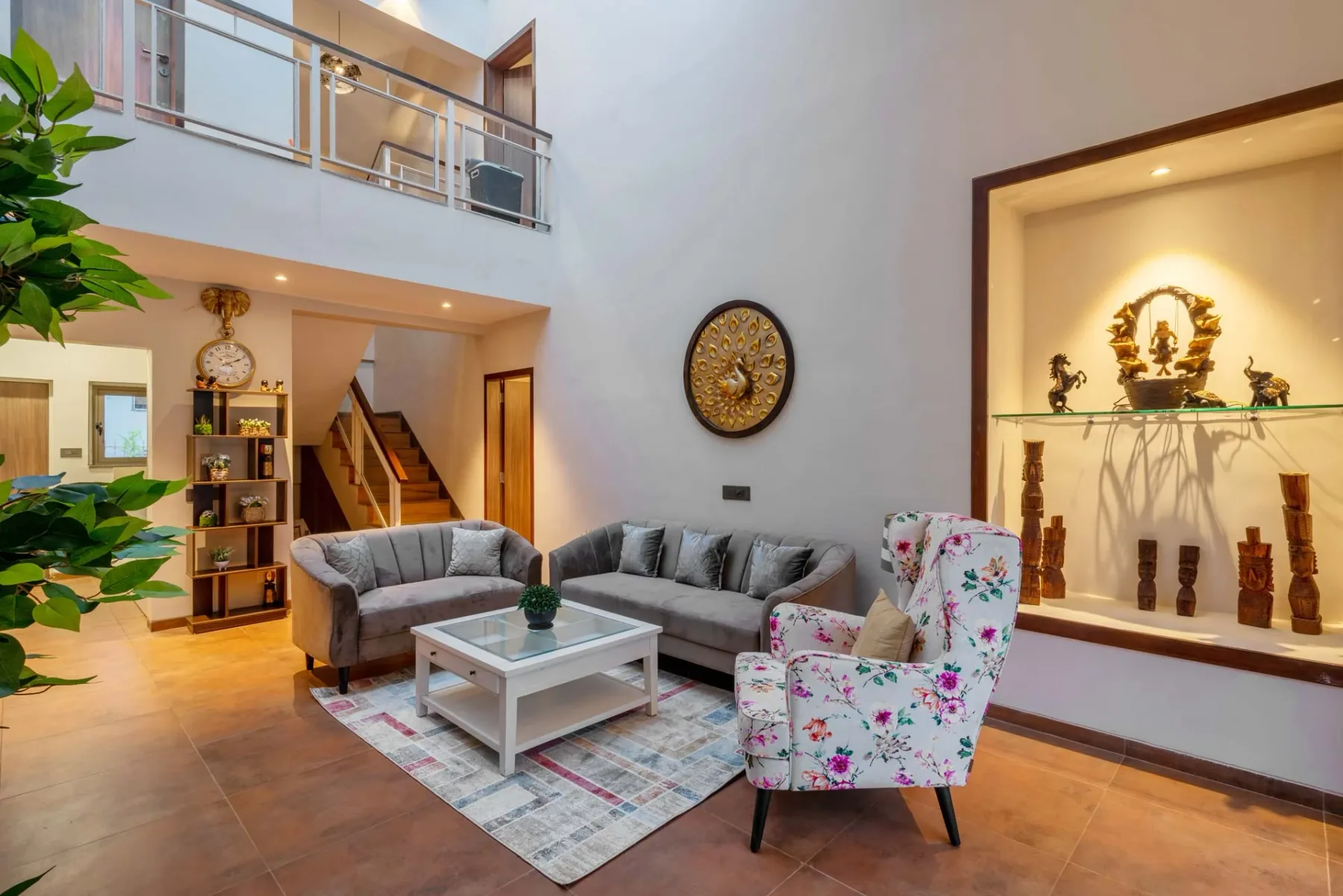 Una sala de estar con asientos grises, una mesa de centro y un sillón floral.