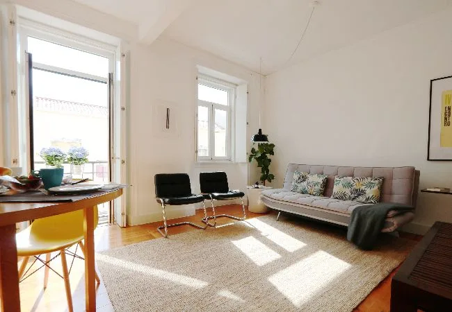 A bright living room with a sofa, lounge chairs, and a large rug.