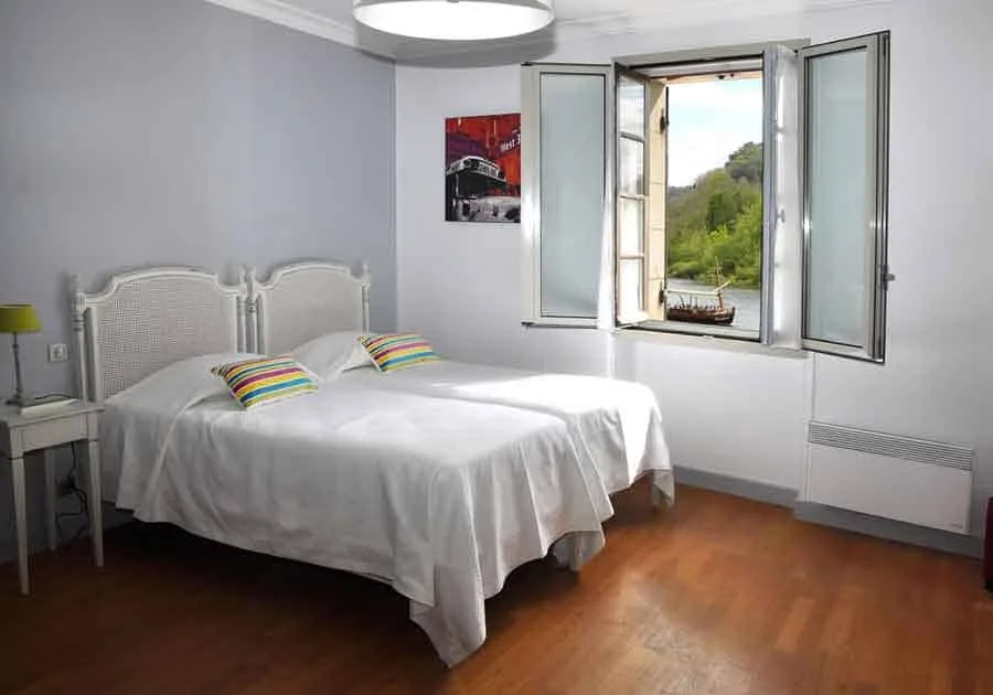 Espacio representativo del hotel: Un dormitorio con dos camas junto a una ventana abierta con vistas a la vegetación.