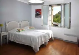 Espacio representativo del hotel: Un dormitorio con una cama blanca junto a una ventana abierta.