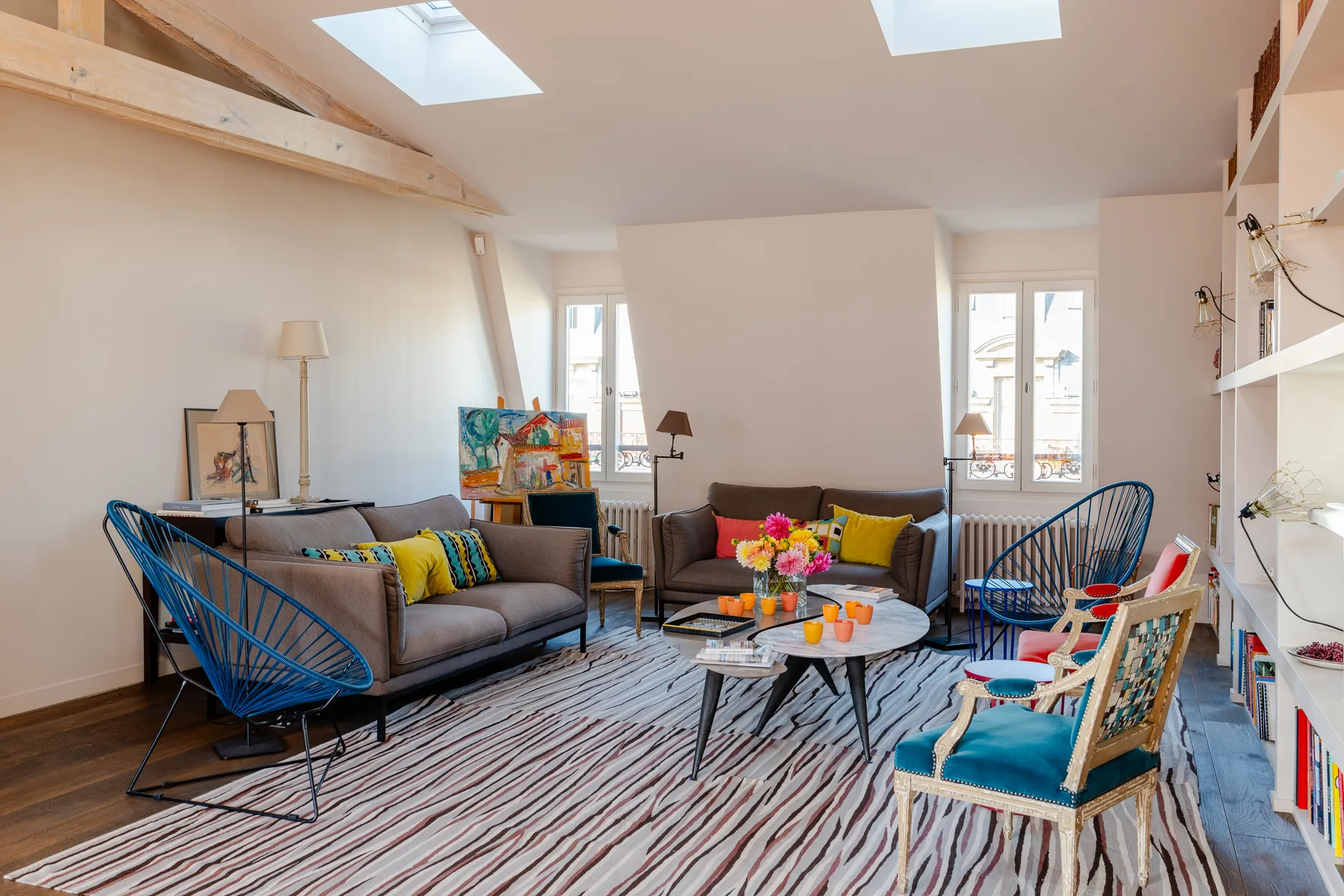 A bright living room has seating around a coffee table beneath skylights.