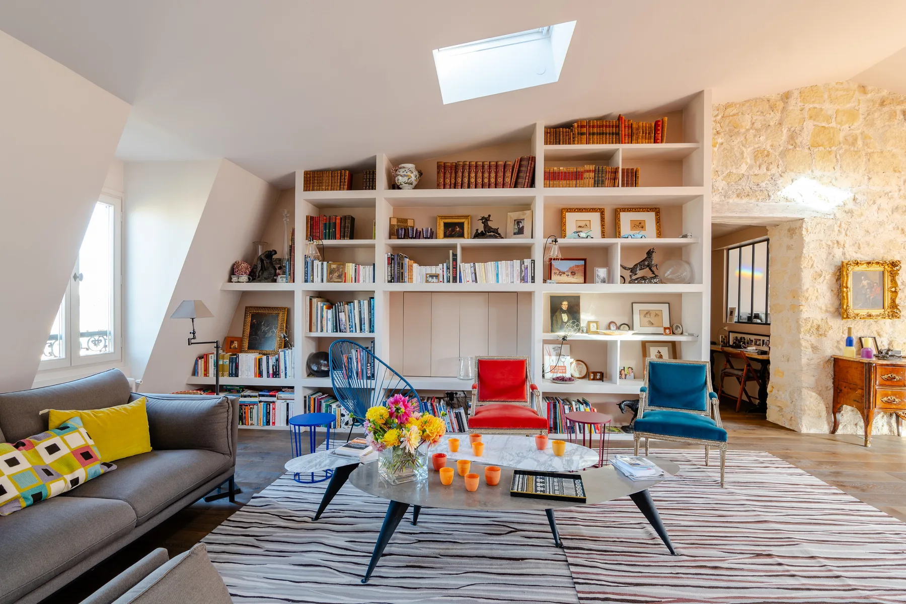 A bright living room with a large bookcase and colorful seating.
