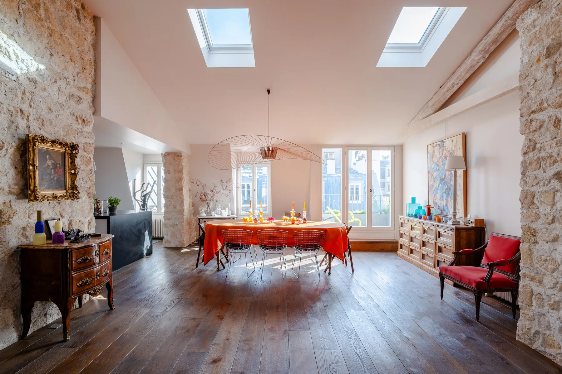 A bright dining room with a long table beneath skylights and tall windows.