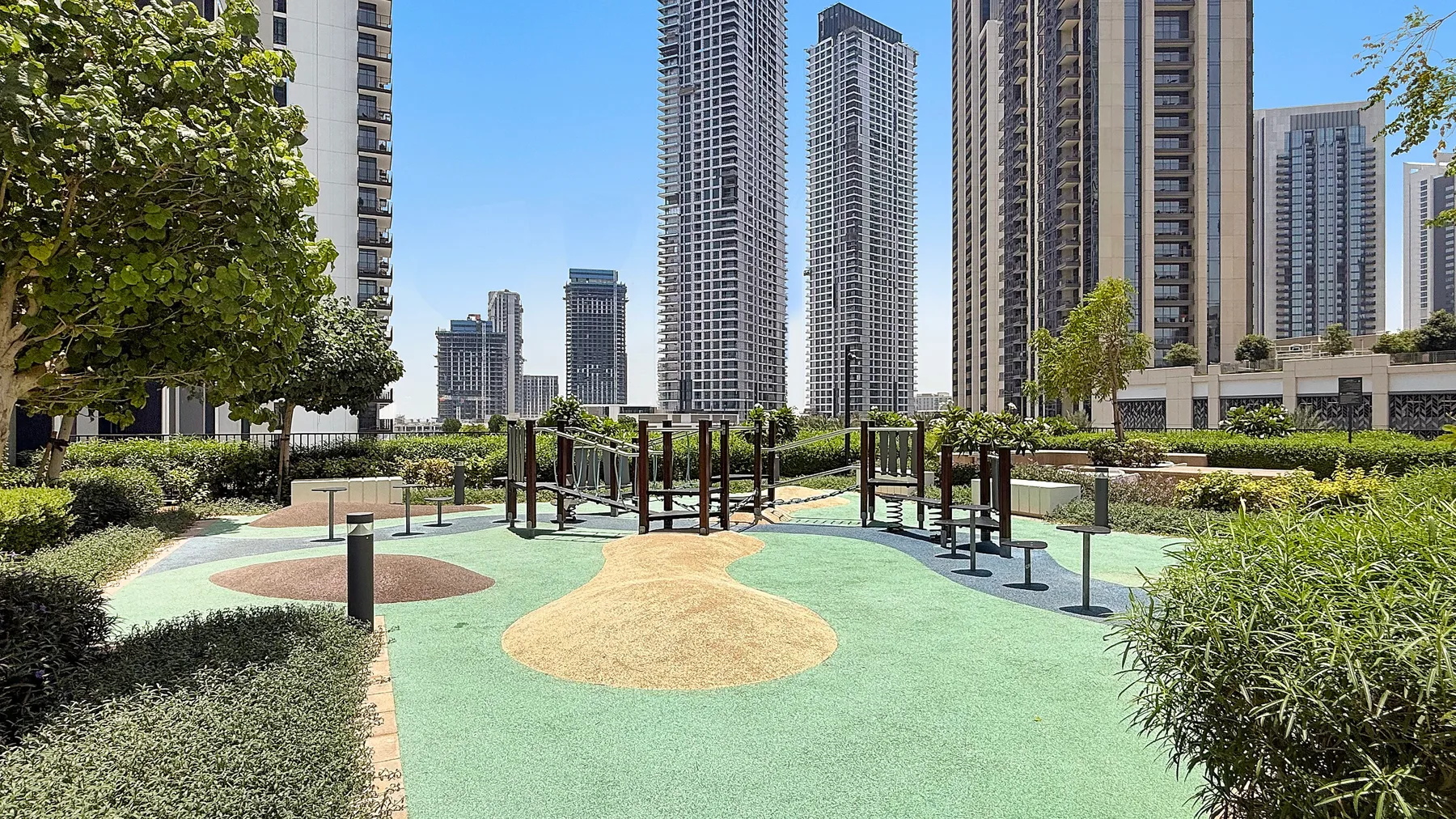 Shared amenity: An outdoor exercise area with fitness equipment among landscaped grounds and tall buildings.